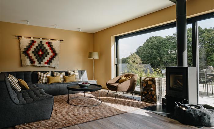 A lounge with a wood burner and large windows looking out to the patio